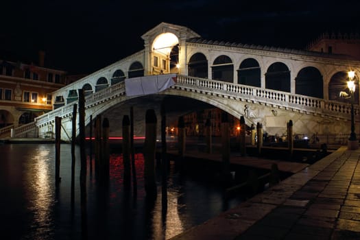 Night shot of the famous Rialto Bridge in Venice, Italy spanning over the Grand Canal.