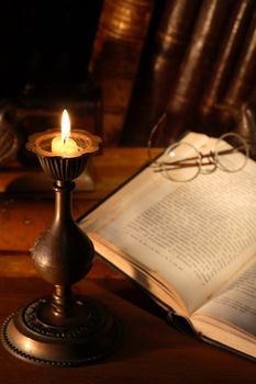 Vintage still life with old book near lighting candle