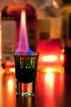 Burning cocktail in shot glass on a table, shallow focus