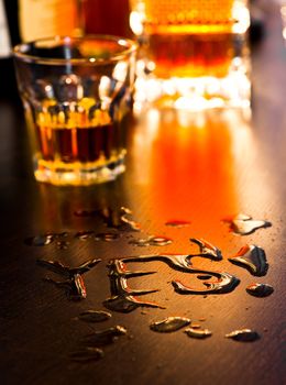 The word Yes written with spoiled whiskey on a table, shallow DOF