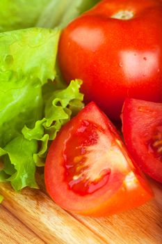 Vegetables (tomato and salad) on a wooden table