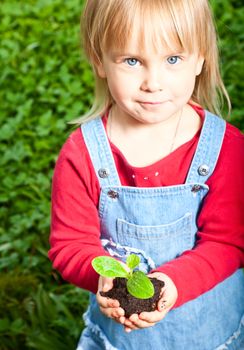 Blonde girl showing seeding with ground, focus on sprout