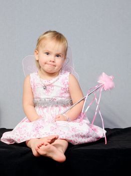 Portrait of cute little girl wearing wings holding wand