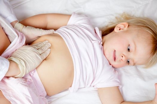 Pediatrician examining little girl's abdomen using manual palpation