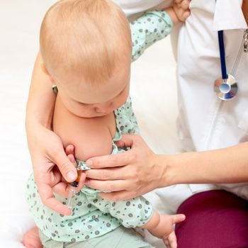 Doctor giving a child an intramuscular injection in arm, shallow DOF