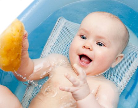 Little baby girl bathing with sponge