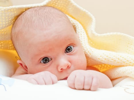 Newborn baby girl lying under yellow towel