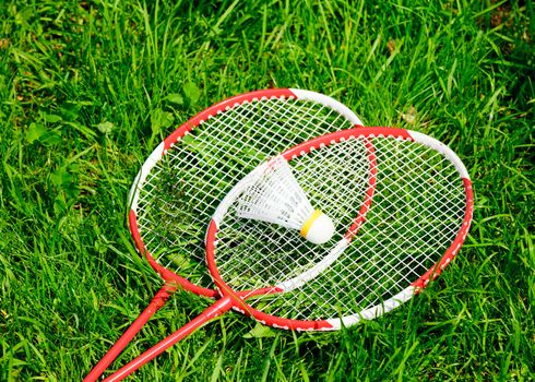 Badminton racquets with shuttlecock on fresh grass