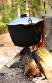 Camping kettles over burning campfire