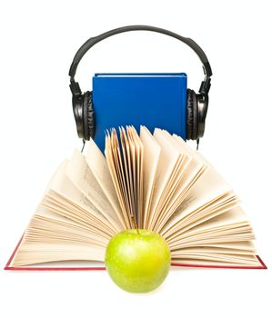 Open book with green apple and HI-Fi headphones on blue book at background