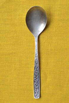 vintage silver spoon on the yellow tablecloth background
