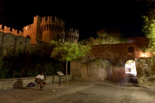 A long exposure motion blurs a local buslter outside the Place of the Grand Masters in Rhodes