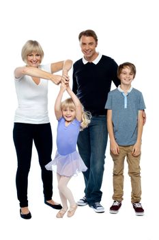 Mother helping her little ballerina twirl. Father and son looking at the camera.