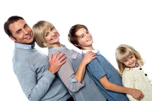 Cheerful family of four leaning backwards on one other, having fun.