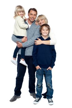 Affectionate family of four posing in winter outfits. Full length studio shot.