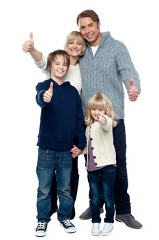 Adorable family in winter clothes gesturing thumbs up. Full length portrait over white background.