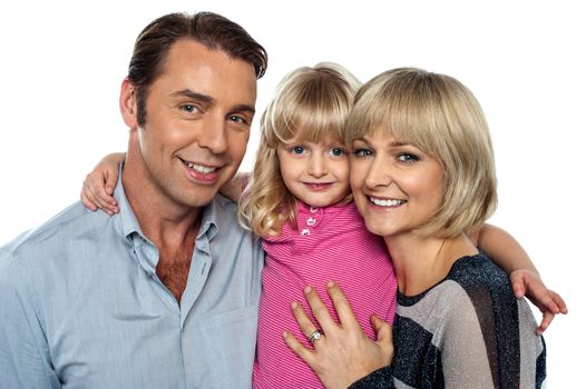 Stylish little daughter embracing her parents. All facing camera and smiling.