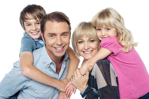 Fun loving family of four. Kids enjoying piggy ride. Indoor studio shot.