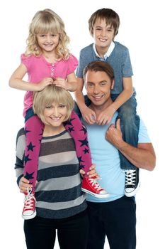 Cute daughter and son riding on their parent's shoulders. All on white background.