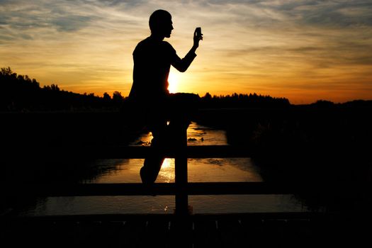 A person sitting on a brigde and making a photo A person sitting on a brigde and making a photo