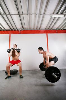 Group of two people exercising using barbells in gym and kettlebell crossfit workout