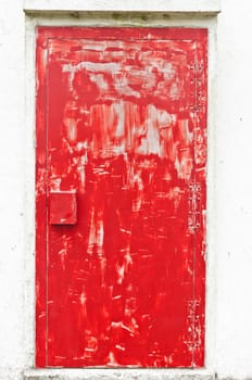 Red colored weathered door of a lighthouse, the paint is uneven