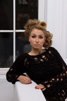 portrait of beautiful young blond woman with handbag sitting on couch