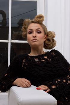 portrait of beautiful young blond woman with handbag sitting on couch