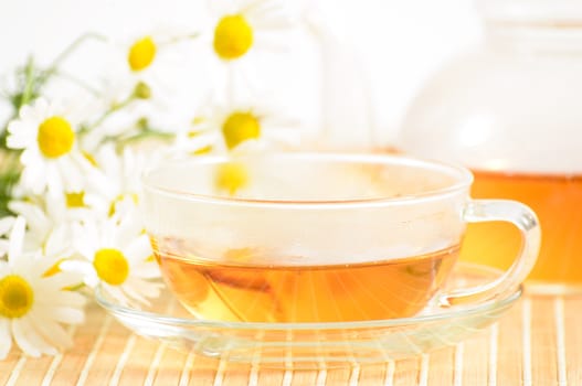 A teacup and a teapot with herbal chamomile tea