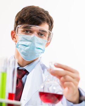 Portrait of a scientist working in the lab examines a test tube with liquid