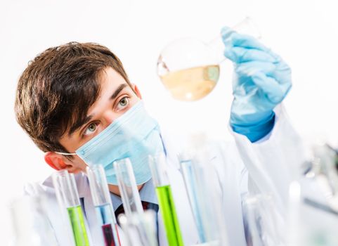 Portrait of a scientist working in the lab examines a test tube with liquid