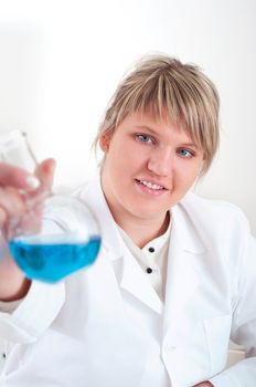 female chemist mixing liquids in test tubes, working in lab