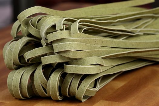 beautiful fresh and raw spinach fettuccine on fine wood kitchen station close up
shallow DOF  