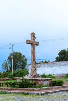 cross in front of Oxtotipac church and monastery, Mexico. The former Convent of St. John the Evangelist is  icon of the historic architecture of Teotihuacan is located just 3 km from the archaeological site, the site was built during the year 1548 and served as nucleus for the Franciscans. In his church stands a fine old tower and a steeple.