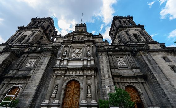 The Metropolitan Cathedral of the Assumption of Mary of Mexico City is the oldest and largest cathedral in the Americas and seat of the Roman Catholic Archdiocese of Mexico. It is situated atop the former Aztec sacred precinct near the Templo Mayor on the northern side of the Plaza de la Constitución in downtown Mexico City. The cathedral was built in sections from 1573 to 1813 around the original church that was constructed soon after the Spanish conquest of Tenochtitlán, eventually replacing it entirely. Spanish architect Claudio de Arciniega planned the construction, drawing inspiration from Gothic cathedrals in Spain.