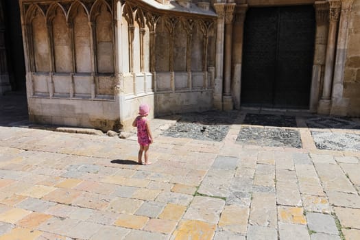 Baby girl and bird in the old Spanish town. Near church.