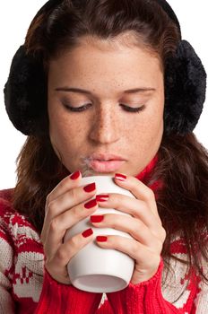 Young woman drinking a hot drink from a white mug, isolated in a white background