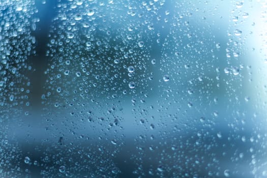 A clean and abstract background texture of a wet window covered in water drops.