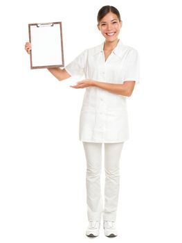 Nurse showing blank clipboard sign - a medical concept. Woman doctor / nurse smiling happy isolated on white background in full body. Mixed race Caucasian / Chinese Asian female model.