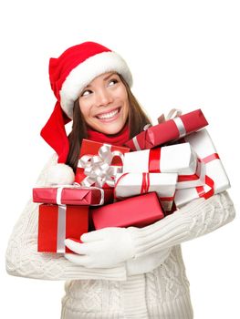 Christmas shopping woman holding gifts smiling happy looking up to the side isolated on white background. Cute Santa girl wearing warm sweater and santa hat holding many christmas presents. Mixed race Asian Caucasian female model.