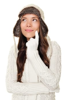Thinking winter woman looking pensive to the side and up wearing warm winter clothing - sweater and tuque wool cap. Happy smiling woman isolated on white background. Asian Caucasian female model.
