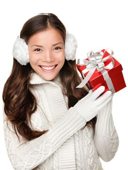 Christmas winter girl holding red present wearing warm sweater and ear muffs. Young beautiful and cute multi-racial woman with lovely smile isolated on white background.