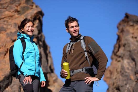 Young couple hiking. Outdoors hikers portrait mountain scenery. Asian woman and Caucasian man.