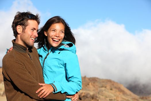 Happy couple smiling outdoors on hiking trip. Young mixed asian caucasian couple enjoying nature.