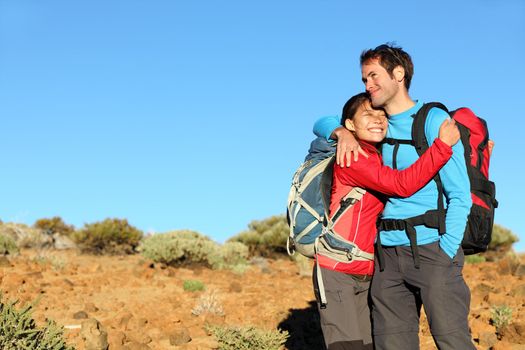 Happy couple healthy lifestyle affectionate outdoors in nature during hiking travel. Man and woman hikers smiling in mountain desert landscape.