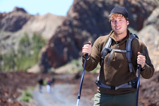 Adventure hiking man. Portrait in mountain landscape. Caucasian male hiker smiling in nature standing with hiking poles in volcano landscape on Teide, Tenerife, Canary Islands