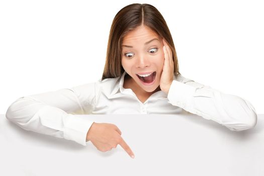 advertising banner sign - woman excited pointing looking down on empty blank billboard paper sign board. Young business woman isolated on white background.