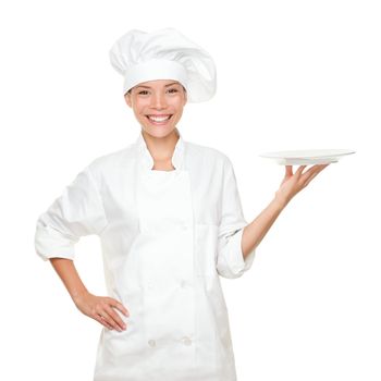 Chef showing empty plate. Happy smilng portrait of female in chef uniform and chef hat isolated on white background. Asian Caucasian woman model.