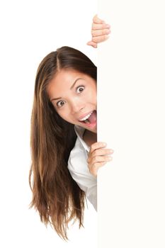 Sign people - woman peeking out from behind billboard paper poster. Excited woman looking surprised at camera. Beautiful brunette with long hair. Asian Caucasian female model isolated on white background