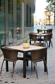 Tables with chairs of a sidewalk cafe beside office building in London